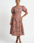 Model wearing the Fanm Mon Aviva Dress featuring scattered black horse embroidery, short puff sleeves, a fitted bodice, and a gathered drop-waist midi skirt.