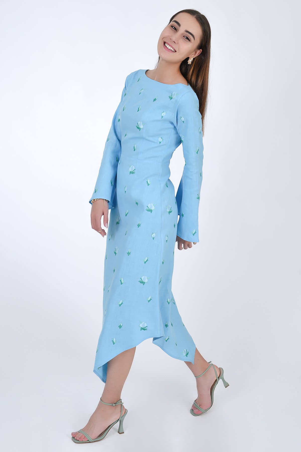 Fanm Mon Choupet Asymmetrical Linen dress, side view.  Features long bell sleeves,  a boat neckline and hits mid length. Detailed with intricate floral-inspired embroidery a Fanm Mon signature.