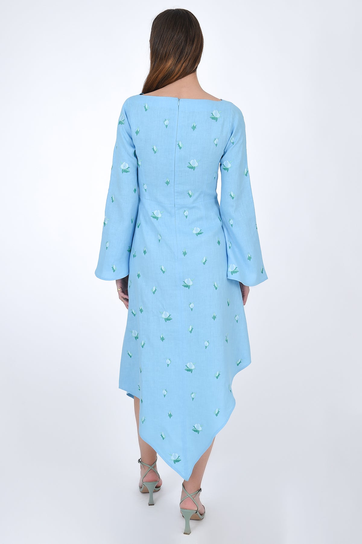 Fanm Mon Choupet Asymmetrical Linen dress, back view.  Features long bell sleeves,  a boat neckline and hits mid length. Detailed with intricate floral-inspired embroidery a Fanm Mon signature.