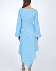 Fanm Mon Choupet Asymmetrical Linen dress, back view.  Features long bell sleeves,  a boat neckline and hits mid length. Detailed with intricate floral-inspired embroidery a Fanm Mon signature. 