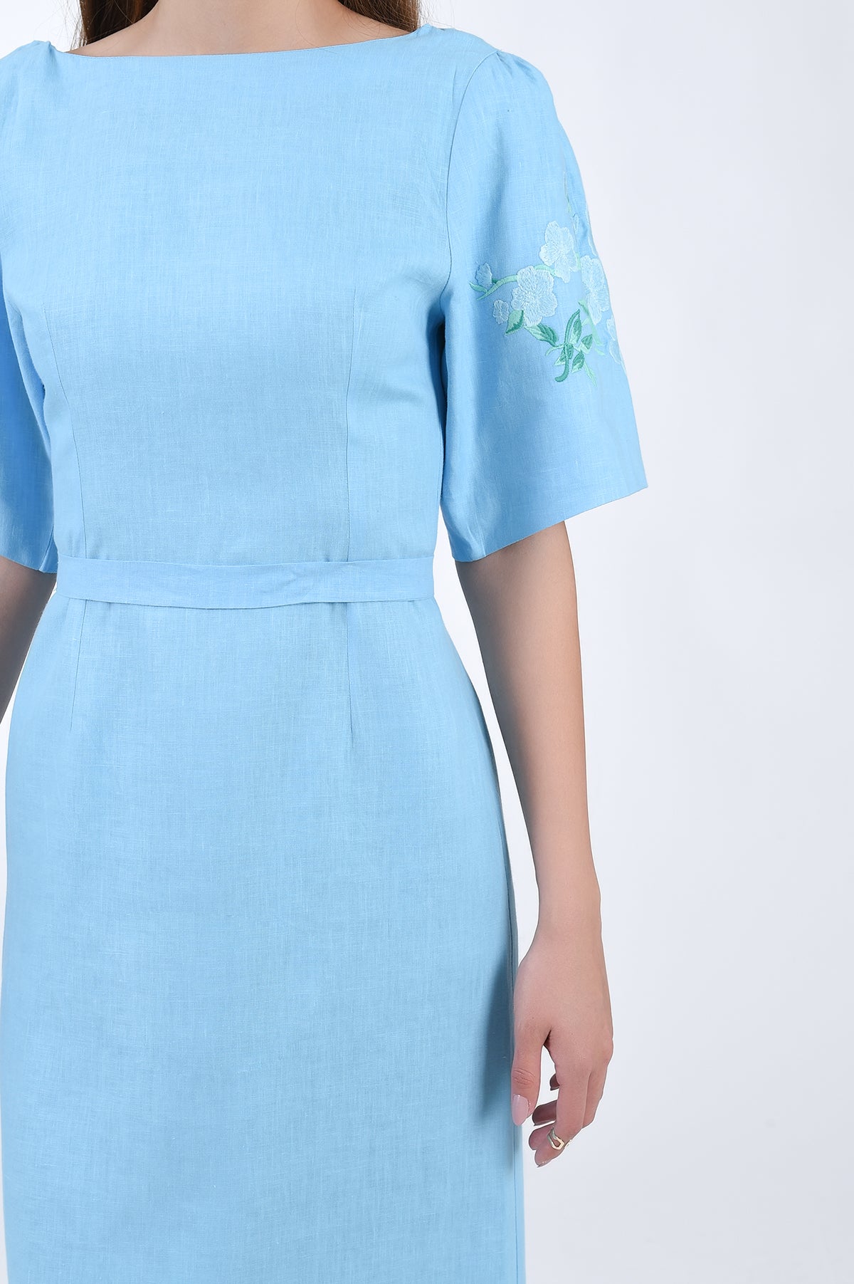 Linen Naif Detail view of sleeve, embroidery, and waist belt.