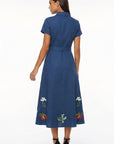 Back view of the Fanm Mon Elena Dress with short sleeves, defined waistband, and botanical embroidery placed around the lower skirt.