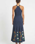 Back view of Erva Dress showcasing embroidered halter midi dress featuring a fitted silhouette and floral embroidered hem.