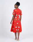 Model wearing the Fanm Mon Hannah Dress featuring tulip and poppy floral embroidery, short sleeves, fitted bodice, and flowing midi skirt in back view against a neutral background.
