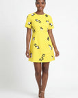 Model wearing the Fanm Mon Hariette Dress featuring jasmine blossom embroidery and trailing botanical vine details on a tailored short sleeve mini silhouette against a neutral background.