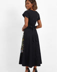 Back view of embroidered midi dress featuring softly structured silhouette and botanical floral embroidery along the skirt panels.
