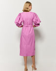 Model wearing a Fanm Mon deep plum dress with puffed sleeves, showcasing back zipper closure and back slit.