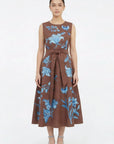 Model wearing the Fanm Mon Gera Dress featuring blue floral embroidery across the bodice and skirt, a round neckline, and self-tie waist belt.