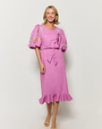 Woman wearing a deep plum cotton short-sleeve fanm mon dress with floral embroidery.