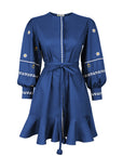 Fanm Mon Noen Dress in indigo blue with white daisy embroidery, blouson sleeves, braided tie waist and ruffled mini hem