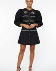 Model wearing the Fanm Mon Pomender Dress featuring a crew neckline, elbow-length puff sleeves, decorative gold-tone buttons, hand-embroidered daisy blossoms and botanical motifs, and an A-line mini silhouette.