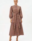 Model wearing the Fanm Mon Samara Dress featuring floral embroidery, three-quarter blouson sleeves, oversized patch pockets, a self-tie waist belt, and gathered midi skirt.
