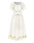 Fanm Mon Selma Dress featuring embroidered lilies, buttercups, cosmos, and botanical vines on a square-neck tiered midi silhouette with a peplum waist.
