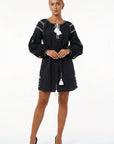 Model wearing the Fanm Mon Stella Dress featuring a gathered neckline, tassel ties, long balloon sleeves, floral embroidery, and a self-tie waist.