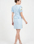 Back view of model wearing Fanm Mon Ether Set in light lagoon showing the fitted bodice, center-back zipper, gathered peplum hem, and tailored mini skirt