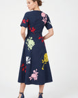 Back view of model wearing Fanm Mon Gandi Dress in navy with a concealed center-back zipper and multicolored floral embroidery across the bodice and A-line skirt