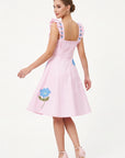 Back view of model wearing the Fanm Mon Hype Dress with embroidered ruffle straps and blue floral embroidery.
