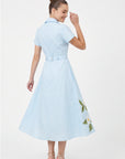 Back view of model wearing Fanm Mon Jahan Dress in light blue featuring an adjustable waist belt, tailored bodice, and flowing A-line midi skirt