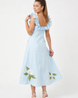 Back view of model wearing Fanm Mon July Dress in light blue with a low square back, ruffled shoulder straps, and floral embroidery along the A-line skirt