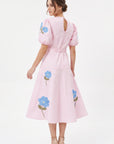 Back view of model wearing the Fanm Mon Lare Dress with puff sleeves, blue floral embroidery and a keyhole back.