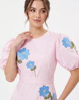 Detail of model wearing the Fanm Mon Lare Dress with blue floral embroidery and voluminous short puff sleeves.