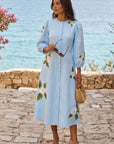 Model wearing the Fanm Mon Paysan Dress in light blue with delicate white floral embroidery and a flowing A-line midi skirt.