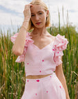 2 Piece Linen Top and Pants Set. Sleeveless top features ruffles with intricate embroidery detail and back detail of bow and button closure, while the wide-leg pants boast a matching embroidery detail and on-seam pockets for a cohesive look.