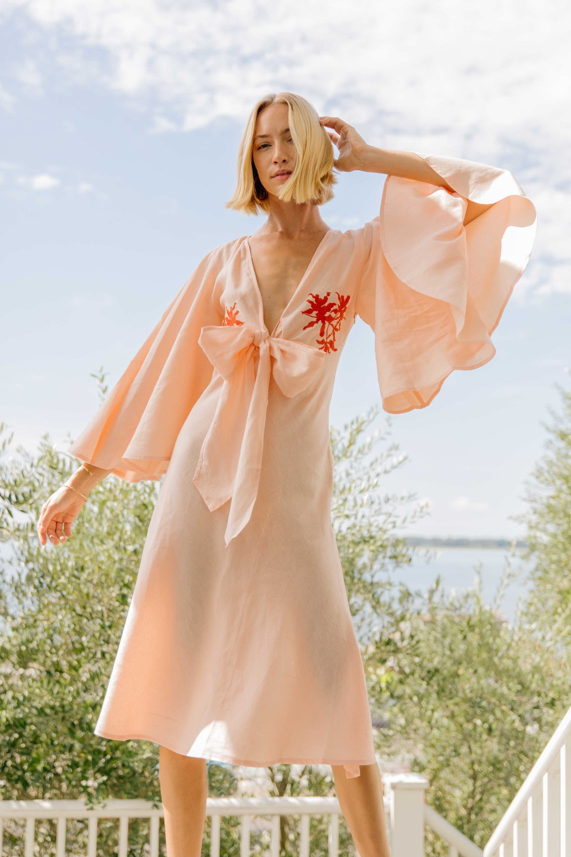 FANM MON DAYNA LINEN DRESS - LIFESTYLE IMAGE.Kimono Sleeve Knee Length Linen Dress. Featuring a biased cut, plunging neckline, embroidery detail on the front, and bow tie front detail.
