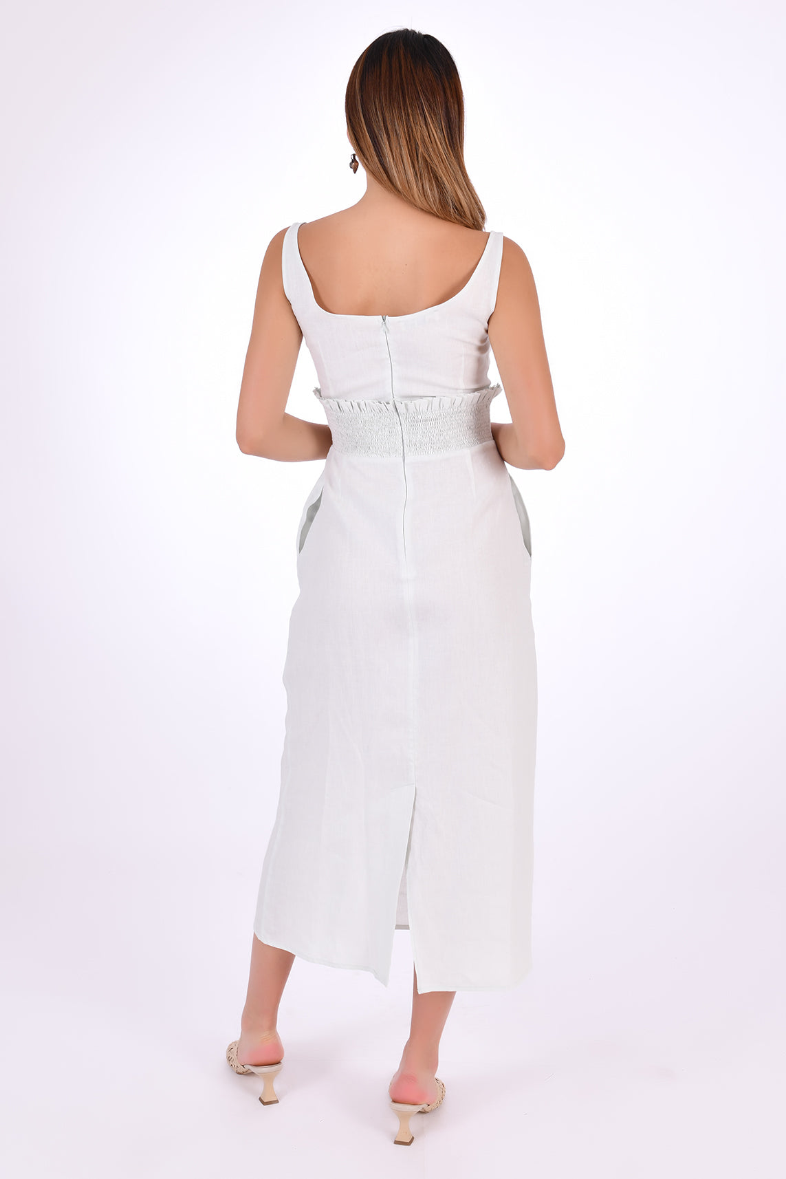 Fanm Mon BAHAR Midi Dress Back View showcase back zipper and slit.. Sleeveless Midi Linen Sheath Dress. Featuring a smocked waistband with ruffle trim and hand-embroidered floral pattern.