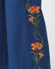 Fanm Mon Arel Pant detail featuring orange and red fire-inspired floral embroidery with green stems and leaves up the sides of the pants.