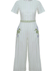 White jumpsuit with green embroidery on a white background. Fanm Mon Birgul Jumpsuit.