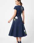 Back view of the Fanm Mon Burma Dress showcasing the fitted bodice, concealed back zipper, removable waist tie, embroidered floral detailing, and flowing A-line midi skirt.