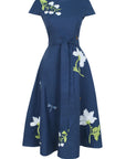 Fanm Mon Burma Dress featuring hand-embroidered anemones, jasmine blossoms, dragonflies, and butterflies on a classic A-line midi silhouette with a removable self-tie waist belt.