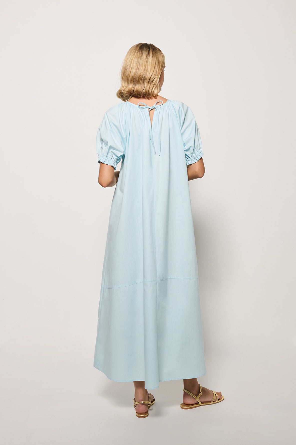 Backview Of Model wearing the  Evora Midi Length dress in Light Lagoon on a white background