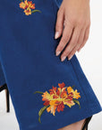 Fanm Mon Cora Pant detail featuring orange and red fire-inspired floral embroidery with green stems and leaves