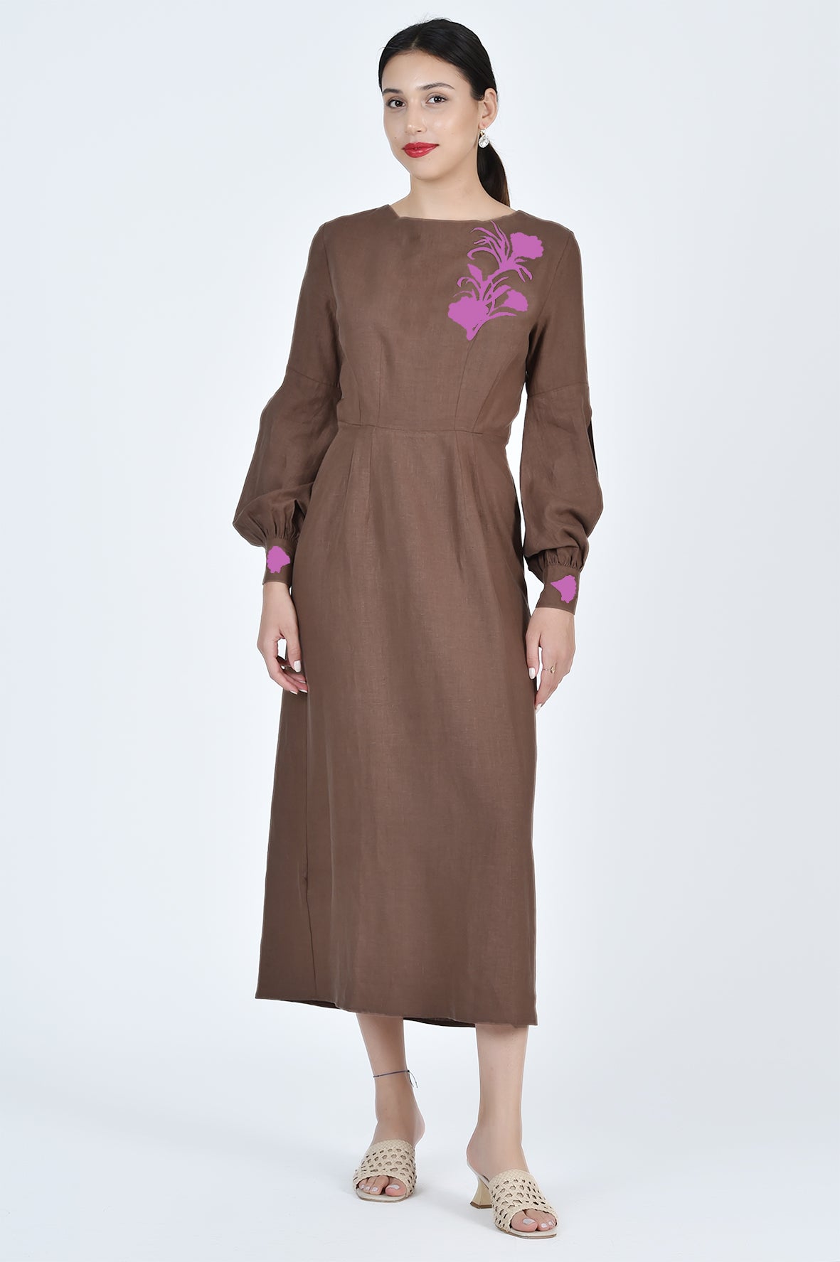 Woman wearing a brown dress with a floral embroidery on a white background