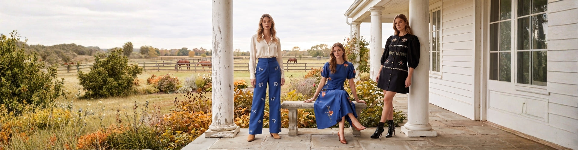 Three women posing on a white porch with columns in front of a rural farmhouse, wearing coordinated outfits including blue jeans and a blue dress.