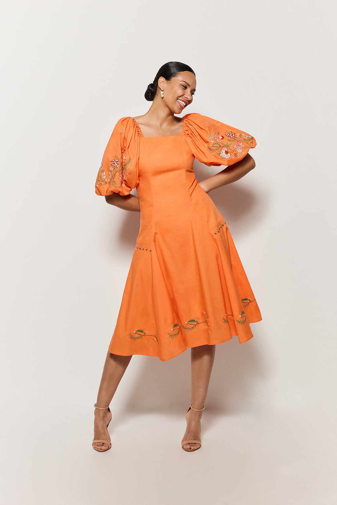 Model wearing Fanm Mon's Cacem Dress in Orange Cotton with floral embroidery details on white background. 