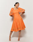 Model wearing Fanm Mon's Cacem Dress in Orange Cotton with floral embroidery details on white background. 