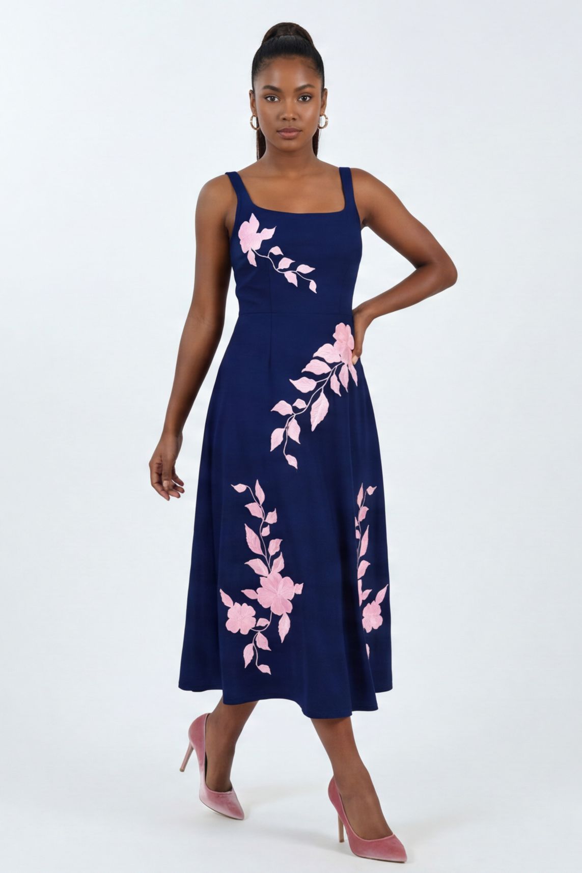 Model wearing the Fanm Mon Elmas Dress with hand-placed hibiscus-inspired floral embroidery, structured square neckline, and elegant midi silhouette against a neutral studio background