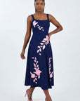 Model wearing the Fanm Mon Elmas Dress with hand-placed hibiscus-inspired floral embroidery, structured square neckline, and elegant midi silhouette against a neutral studio background