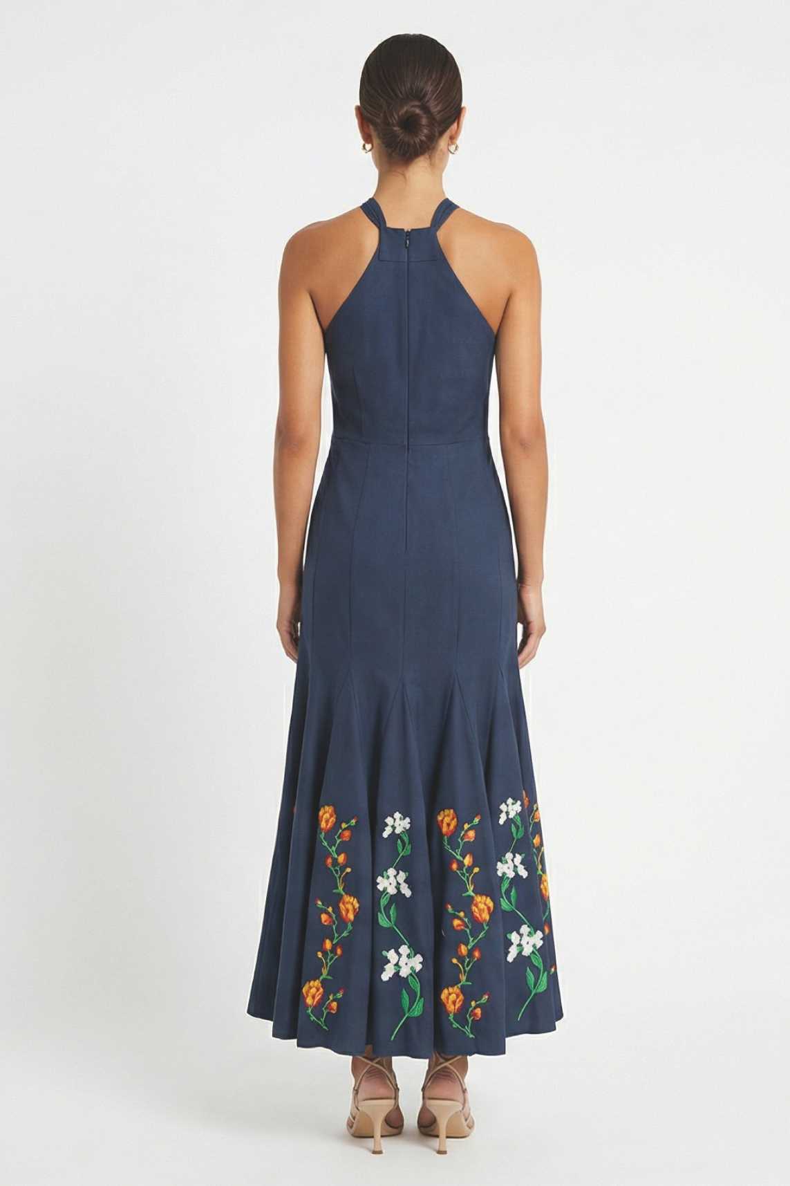 Back view of Erva Dress showcasing embroidered halter midi dress featuring a fitted silhouette and floral embroidered hem.