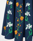 Close-up of hand-placed tulip and jasmine embroidery with intricate botanical detailing on the Erva Dress.