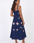 Model wearing the Fanm Mon Fisayo Dress featuring floral vine embroidery, square back neckline, fitted bodice, and midi-length silhouette in back view against a neutral studio background.