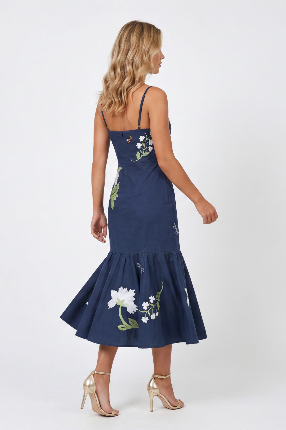 Model wearing the Fanm Mon Gayelle Dress with hand-placed floral embroidery, dragonfly details, adjustable straps, and flounced midi skirt shown from the back against a neutral background.