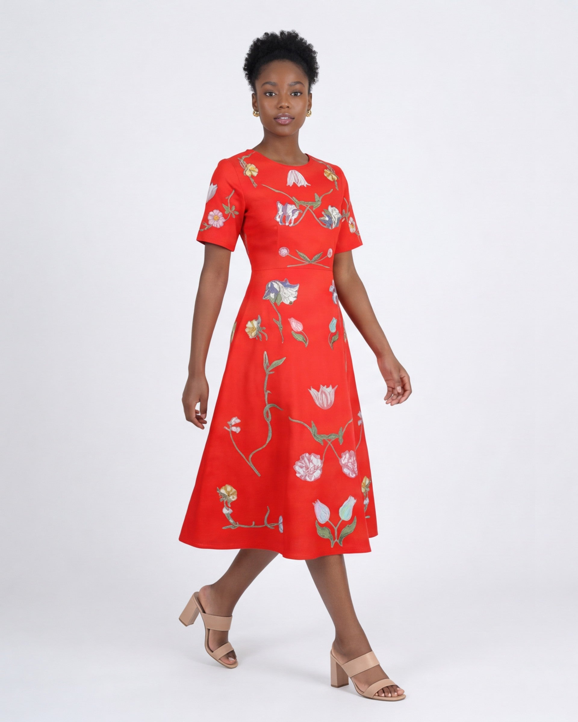 Model wearing the Fanm Mon Hannah Dress with hand-placed tulip and floral embroidery, round neckline, short sleeves, and elegant midi silhouette in front view against an off-white background.