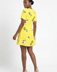Model wearing the Fanm Mon Hariette Dress with scattered jasmine blossom embroidery, short sleeves, and tailored mini silhouette shown from the back against a neutral  background.