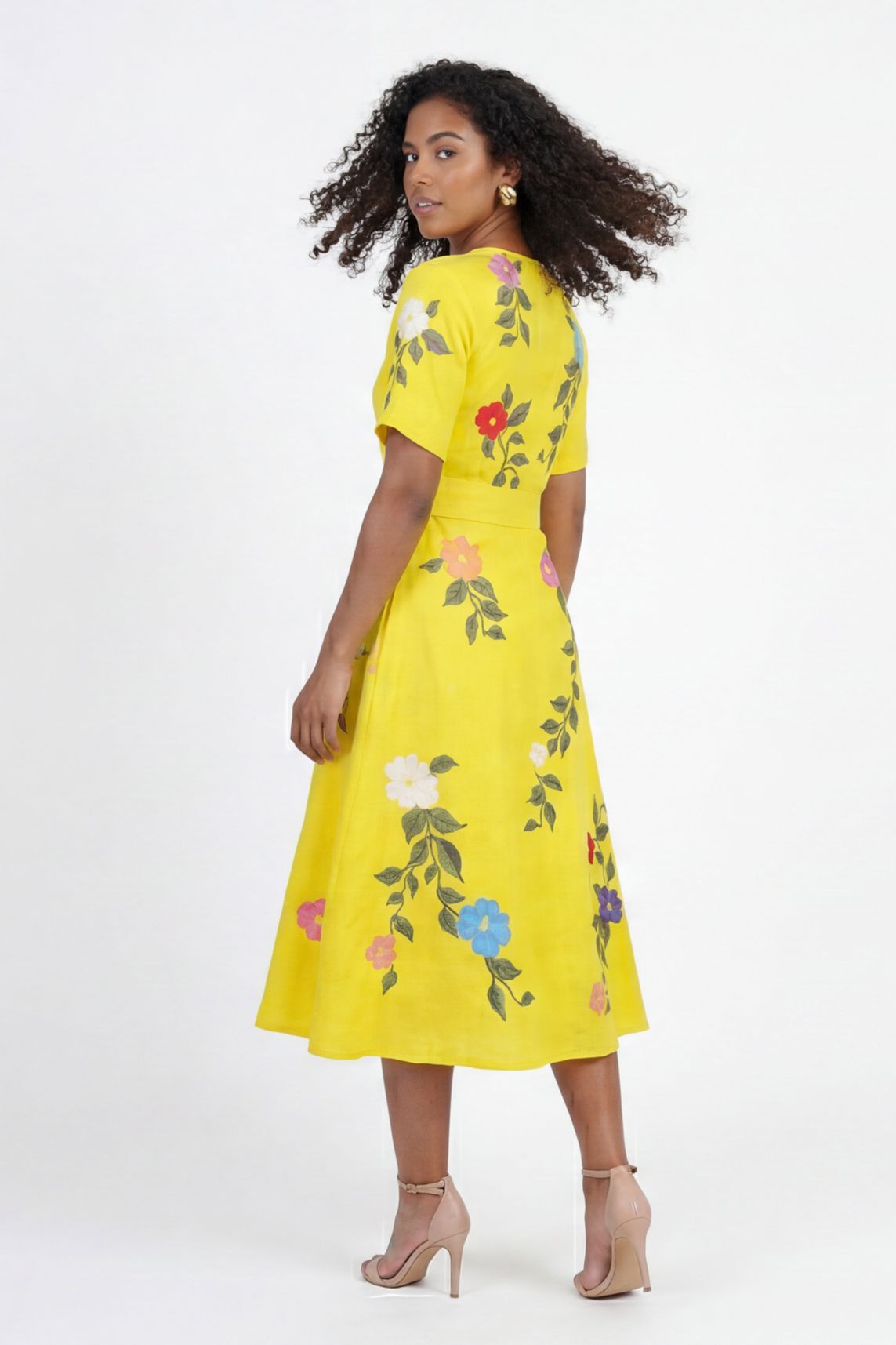 Back view of Fanm Mon Jess embroidered midi dress featuring floral botanical embroidery, short sleeves, flowing skirt, and tailored waist silhouette against off white background.
