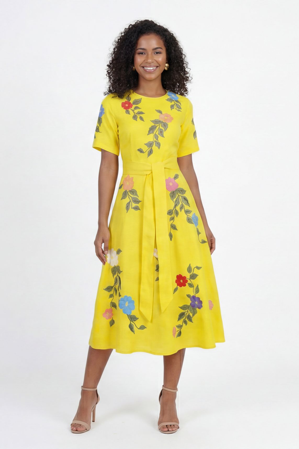 Model wearing Fanm Mon Jess embroidered midi dress with floral botanical motifs, short sleeves, round neckline, and self-tie waist belt against a  off white  background.