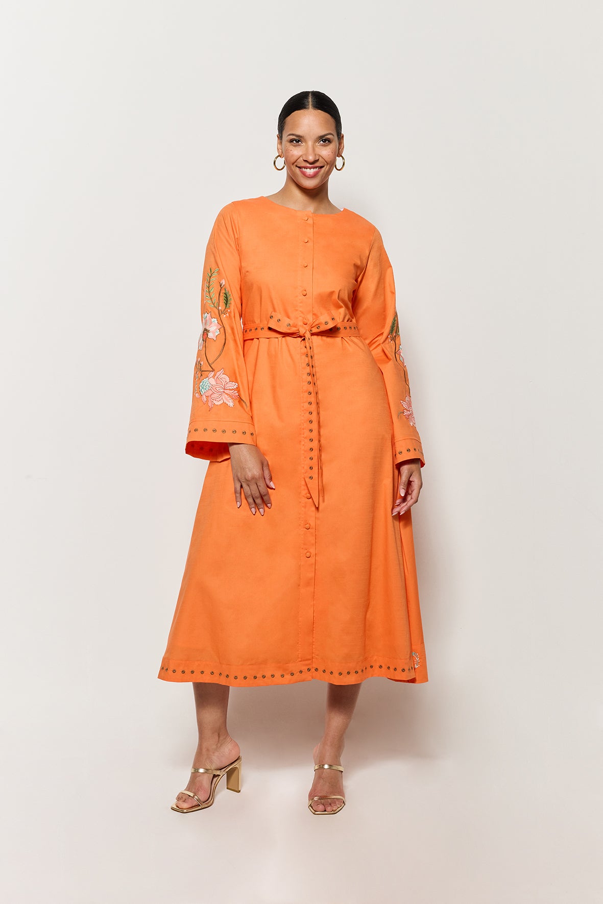 Fanm Mon Long Sleeve Cotton Lagos Dress Shown on Model in Orange, front view of dress with bell sleeves and waist tie. 